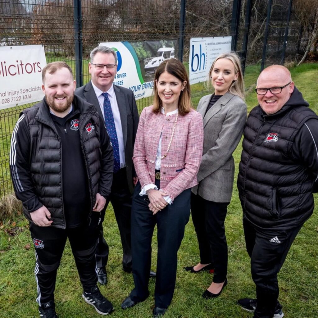 JMK Solicitors Directors standing with Derry City manager in front o the new JMK Sponsorship Banner