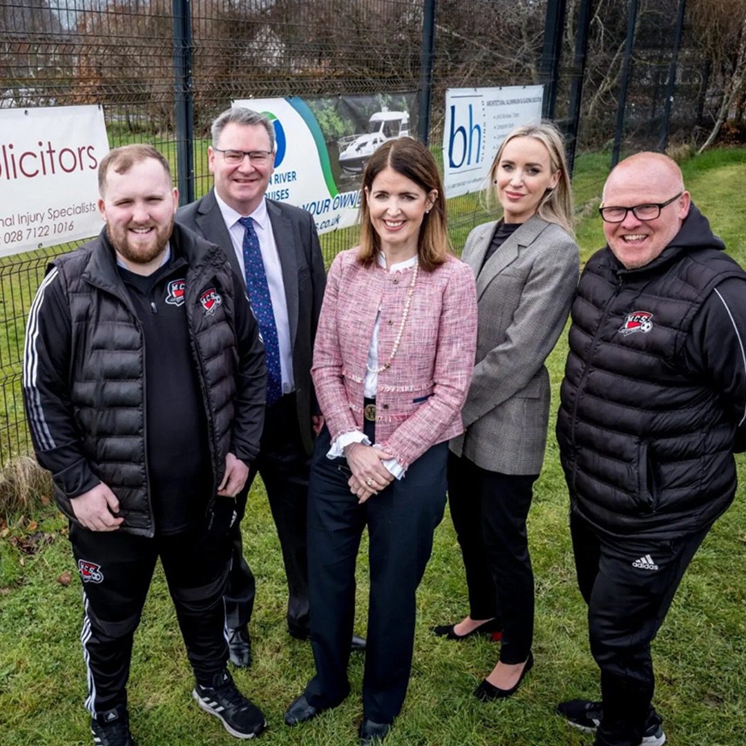 JMK Solicitors Directors standing with Derry City manager in front o the new JMK Sponsorship Banner